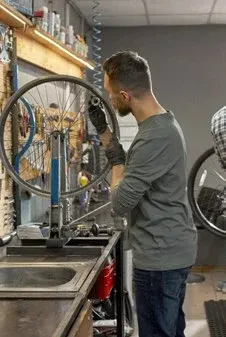 Mechanik v cykloservisu u ponku s koly zavěšenými na stěně