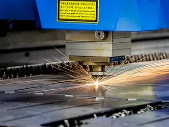Laserový pálicí stroj řeže ocelový plech, od řezu odletují jiskry